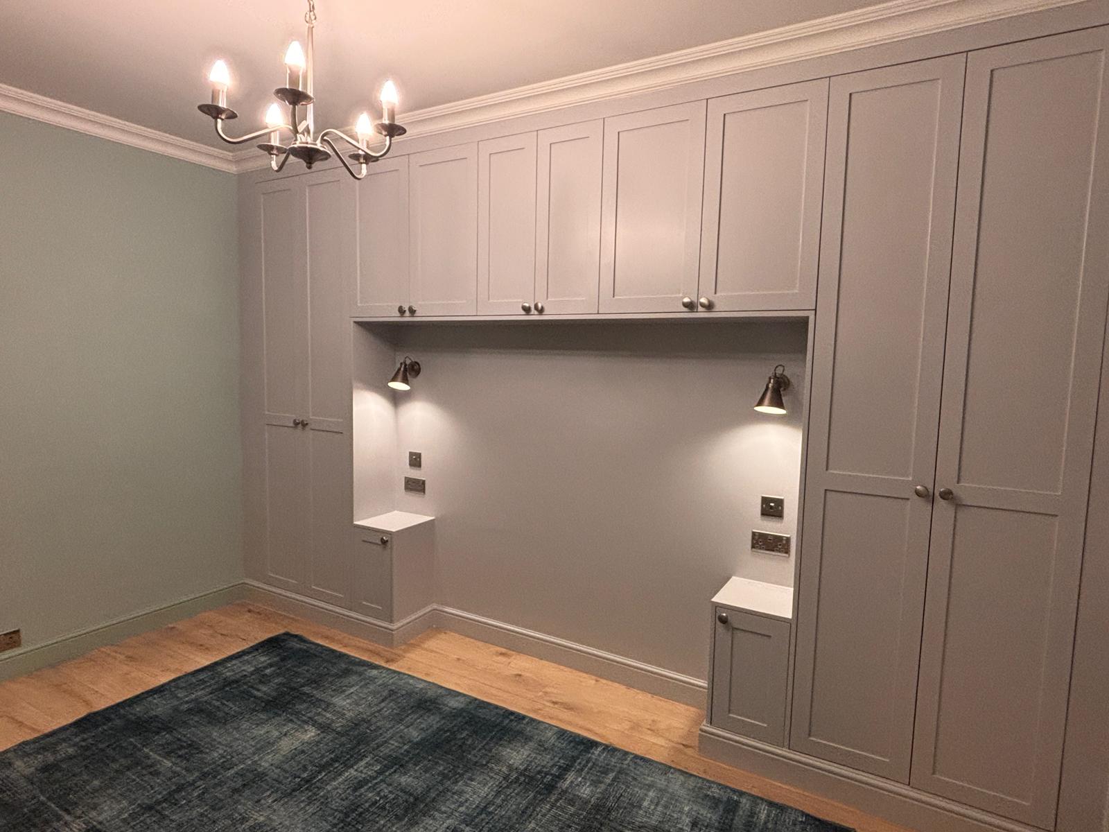 Grey fitted wardrobes with overhead cupboards and integrated bedside cabinets